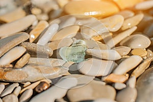 Heart shaped piece of glass on a sea pebble gravel beach, transparent sea. View from the top