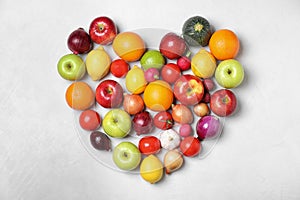 Heart shaped pile of fruits and vegetables on light background