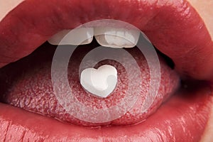 Heart shaped pill in woman's mouth photo