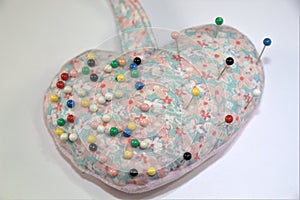 Heart-shaped Pin cushion with pins on white