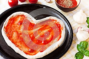 Heart-shaped pizza dough with tomato sauce