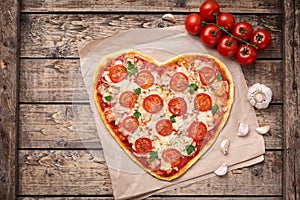 Heart shaped pizza margherita love food symbol with mozzarella, tomatoes, parsley, and garlic composition on cutting