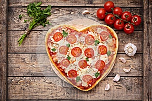 Heart shaped pizza margherita romantic love food concept with mozzarella, tomatoes, parsley, and garlic composition on