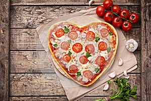 Heart shaped pizza margherita vegetarian love concept with mozzarella, tomatoes, parsley and garlic composition on