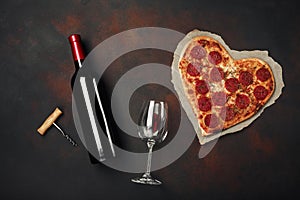 Heart shaped pizza with mozzarella, sausagered and wine bottle, wineglass and corkscrew . Valentines day greeting card on rusty ba