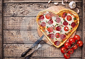 Heart shaped pizza with pepperoni, tomatoes and
