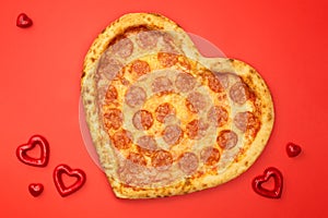 Heart shaped pizza pepperoni for Valentines day on red paper background