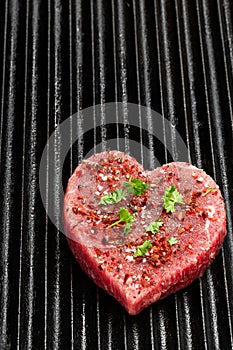 Heart shaped raw beef meat with spices on grill tray. Healthy lifestyle or organic food concept for meat lovers