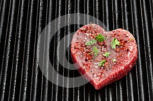 Heart shaped raw beef meat with spices on grill tray. Healthy lifestyle or organic food concept for meat lovers