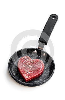 Heart shaped raw beef meat with spices on small frying pan isolated on white. Healthy lifestyle or organic food concept for meat