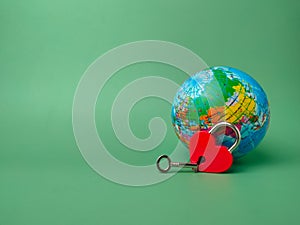 Heart shaped red lock with key and earth globe on a green background.