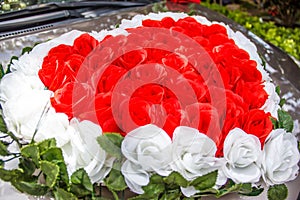 Heart shaped red and white roses wedding flower bouquet in front of the newly wed couple`s car. Sign and symbol of love, wedding photo
