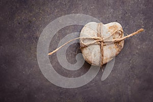 Heart shaped rock pebble tied with twine on dark blue purple stone background, conceptual, relationship, valentine, marriage