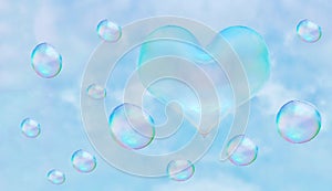 a heart-shaped soap bubble. blue sky background with clouds.