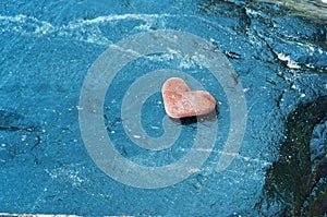 Heart-shaped stone on dark background, red stone heart