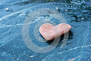 Heart-shaped stone on dark background, red stone heart