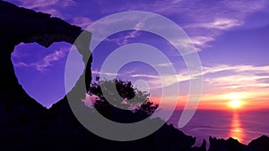 Heart-shaped stone on a mountain with purple sky sunset.