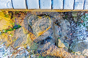 Heart-shaped stone on a wet stone path with remnant of snow