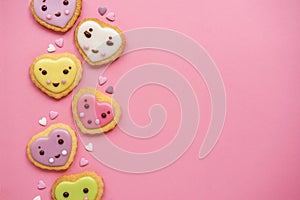 Heart shaped sugar cookies decorated with pastel royal icing on pink background