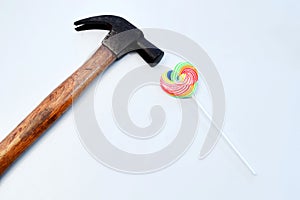 Heart shaped sweet candy and hammer on the white table