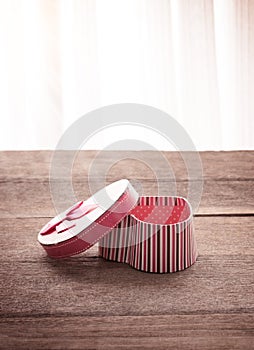 Heart shaped Valentines Day gift box on old vintage wooden plate