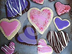 Heart Shaped vanilla and chocolate cookies with pink and purple icing for Valentines day on metal cookie sheet