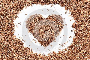Heart-shaped and wood saw dust on dirty white background