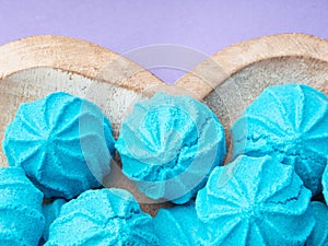 Heart shaped wooden dish with blue sweet meringues on purple