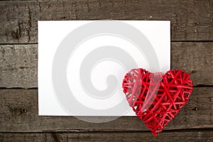 Heart with sheet of paper on a wooden board.