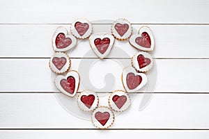 Heart of the shortbread heart-shaped cookies with jam on white wooden table background.