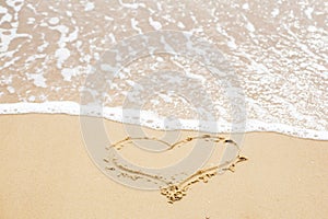 Heart sign on beach. Heart symbol on sandy beach and sea waves with foam. Love and hello summer concept. Vacation, relax and