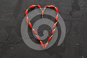 Heart sign of red chili peppers on a black background. blank for designers.