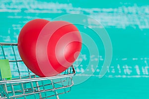 heart sign in shopping cart on color wood