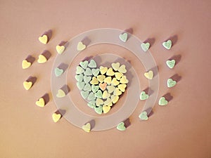 Heart from small hearts tablets, sweet vitamins on tinted paper, top view