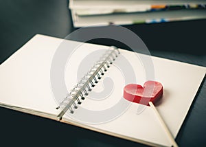 Heart stick on blank notebook on desk