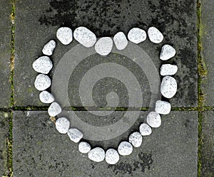 Heart of stone made of small white stones on the dark stone background
