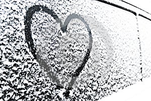 Heart symbol on frozen window of the car. Shape of heart drawn on snow on front window of the car. Heart snow. Christmas decoratio