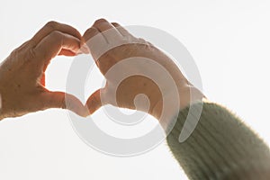 Heart symbol, Heart made by hands with blurry white sky background.Close up