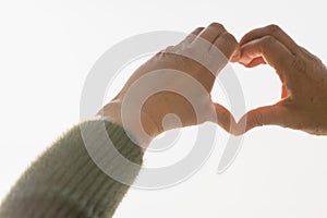 Heart symbol, Heart made by hands with blurry white sky background.Close up