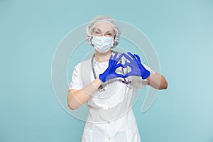 Heart symbol, love. Doctor or nurse woman in a personal protective suit with a stethoscope, on a blue background. In a