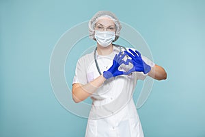 Heart symbol, love. Doctor or nurse woman in a personal protective suit with a stethoscope, on a blue background. In a