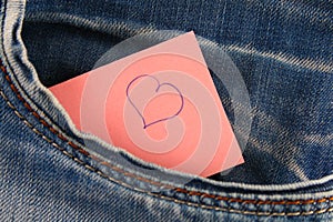Heart - a symbol of love peeps out of the pocket of jeans trousers. The concept of the day of lovers. St. Valentine's Day.