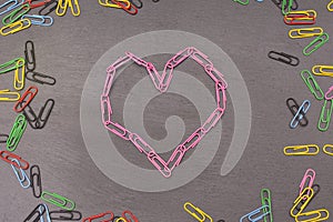 heart symbol made of pink paper clips on a dark background