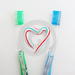 The heart symbol is made from a three-color toothpaste and is located between two toothbrushes