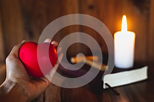 The heart symbol on a woman`s hand A candle lit up the scriptures. Pray for God`s blessing with faith in His power, thoughts of