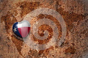 Heart with texas state flag on a vintage world map crack paper background