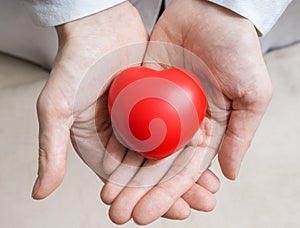 Heart transplantation concept. Doctor holds red heart in hands