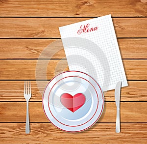 Heart on white plate with fork and knife on wooden table surface