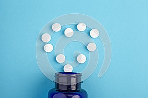 Heart of white tablets spilling out of package, Close up pills spilling out of pill bottle on blue background. Medicine, medical