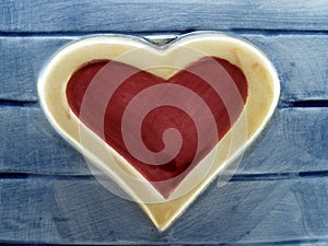 red heart shape with yellow frame on artificial blue wood plank made of painted pottery